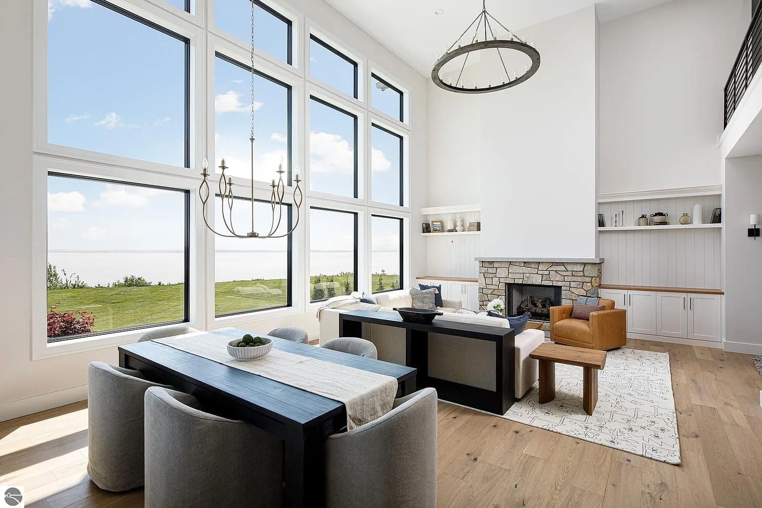 Spacious living room with large windows, modern furniture, and a stone fireplace overlooking a scenic view.
