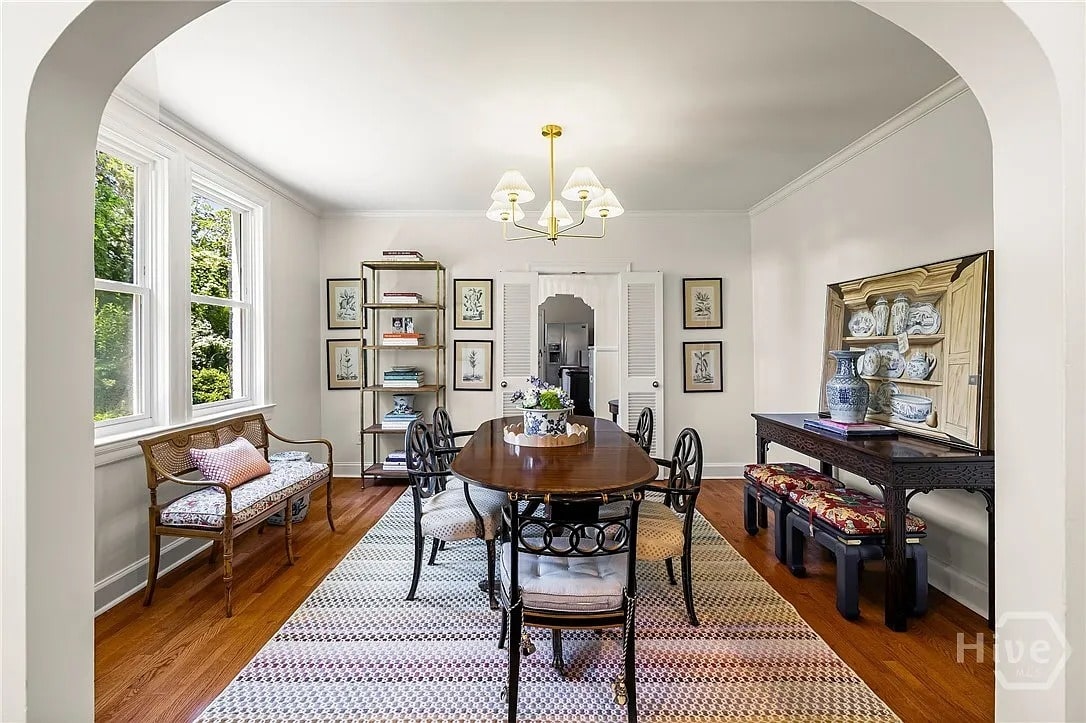 Elegant dining room with a wooden table, chairs, wall art, and large windows.