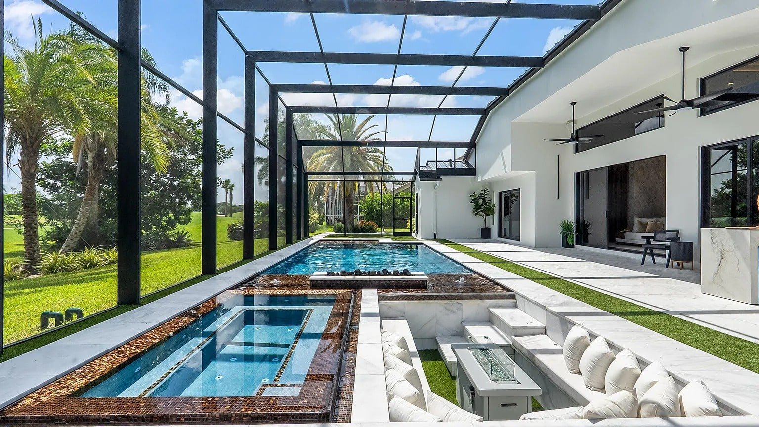 Modern outdoor patio with a pool, hot tub, and sunken seating area under a screened enclosure.