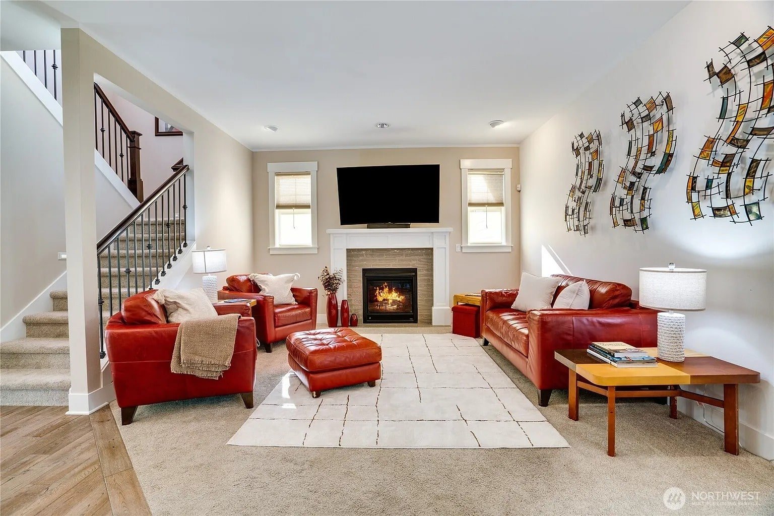 Living room with red leather sofas, a fireplace, wall art, and a large TV above.