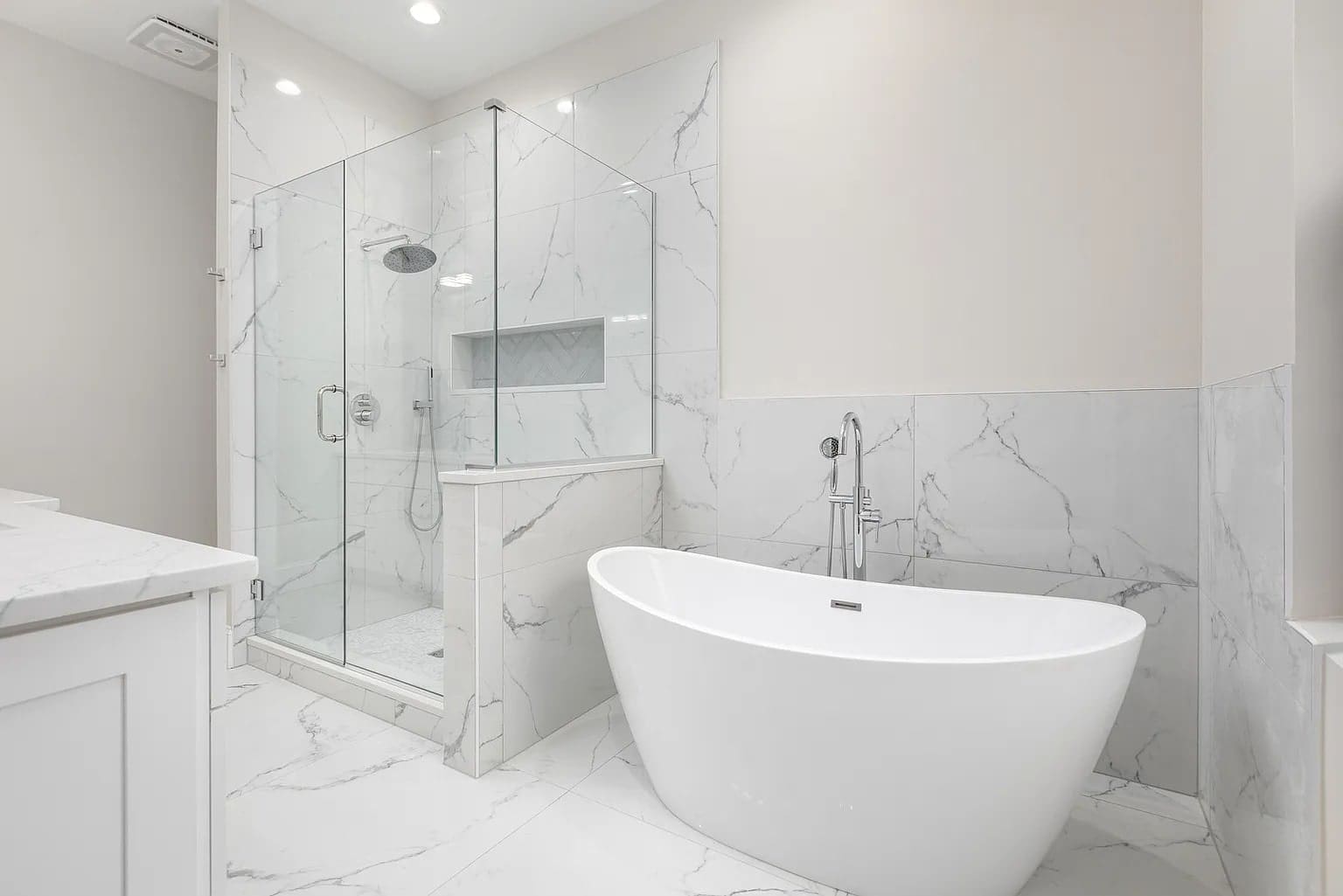 Modern bathroom with a freestanding bathtub and a glass-enclosed shower, featuring marble tile walls.