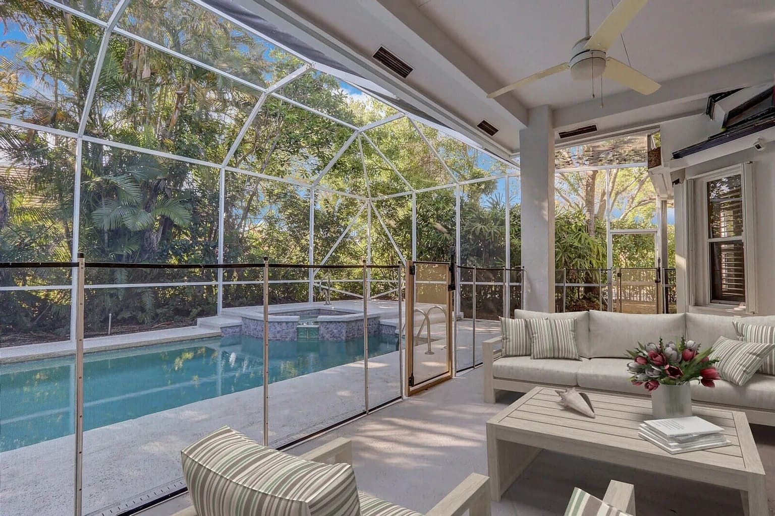 Screened-in patio with seating area overlooking a pool and lush greenery.