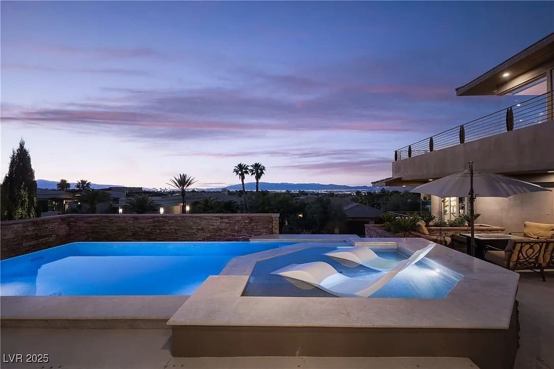 Luxurious outdoor pool and hot tub at sunset, with modern patio and scenic view.