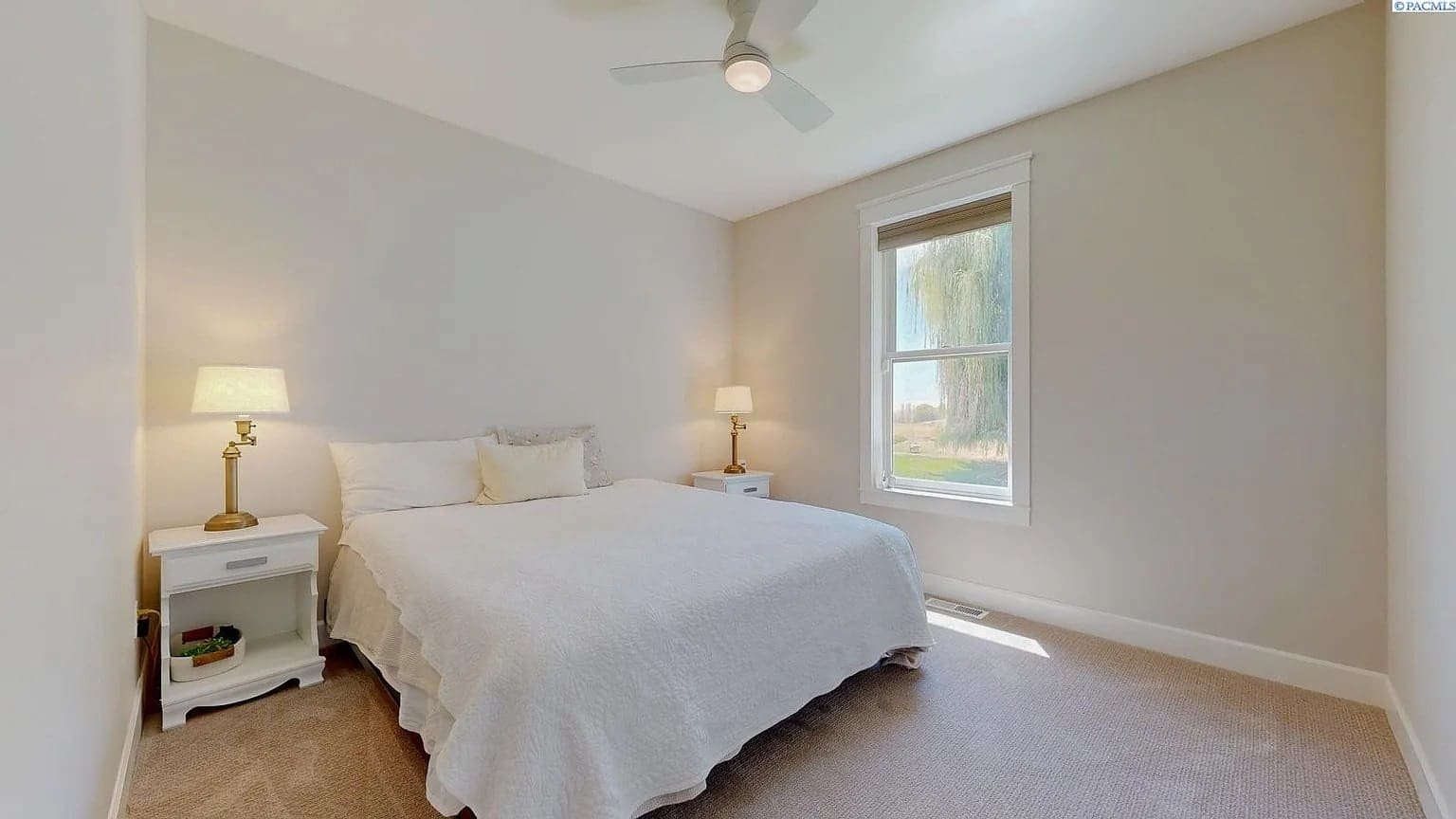Bedroom with a double bed, two bedside tables, lamps, and a window with natural light.