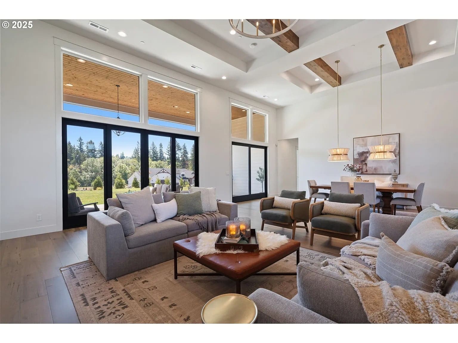Spacious modern living room with large windows, cozy seating, and a dining area.