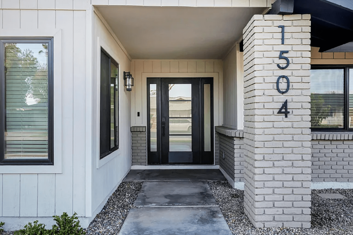 Modern house entrance with double glass doors, brick pillar, and house number 1504 displayed.