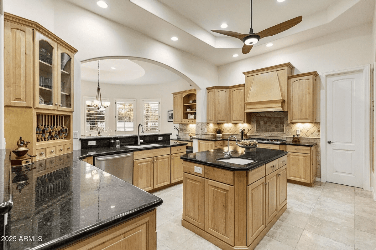 Spacious kitchen with wooden cabinets, black countertops, central island, and modern appliances.