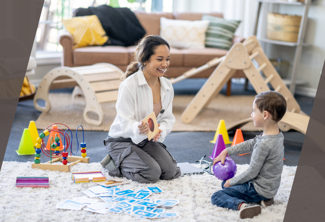 A woman and child engage in educational play with toys and cards in a playroom.