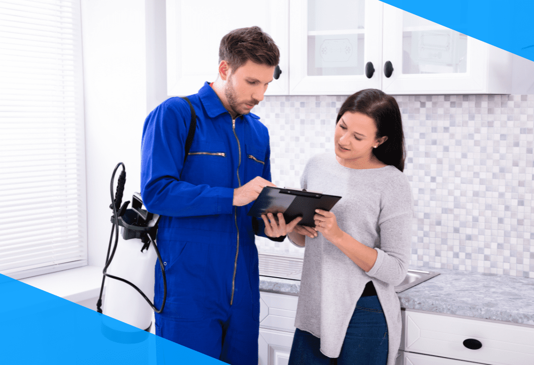 Man in blue uniform showing tablet to woman in kitchen.