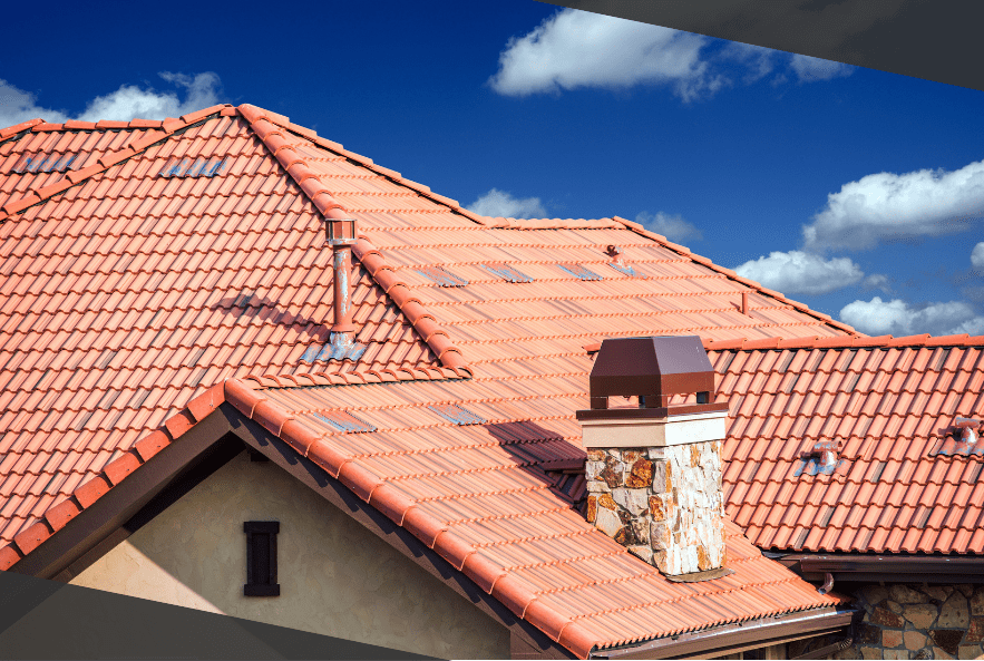 Red tiled roof with chimney against a blue sky with scattered clouds.
