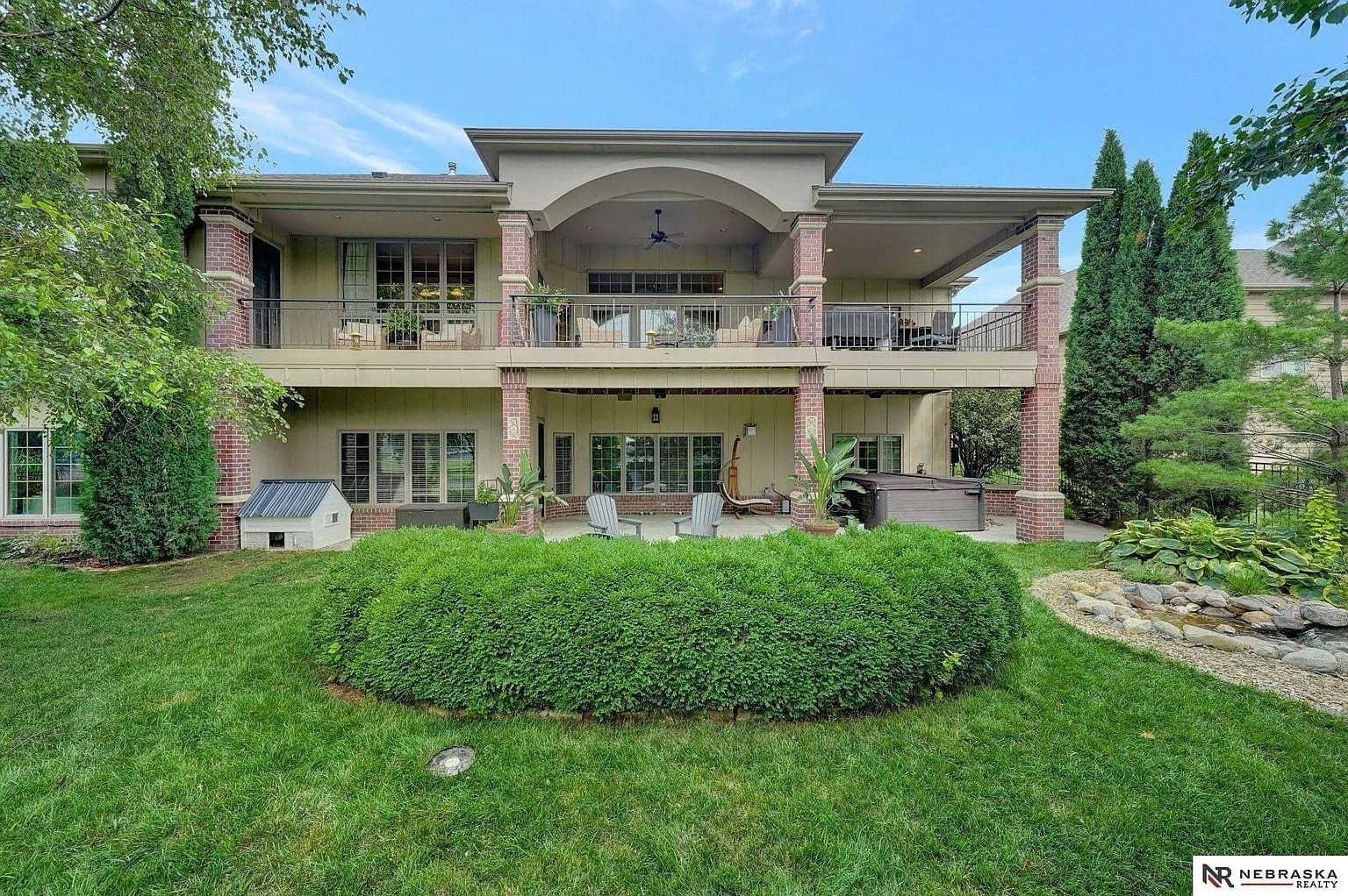 Two-story house with a large balcony, patio furniture, and landscaped garden.