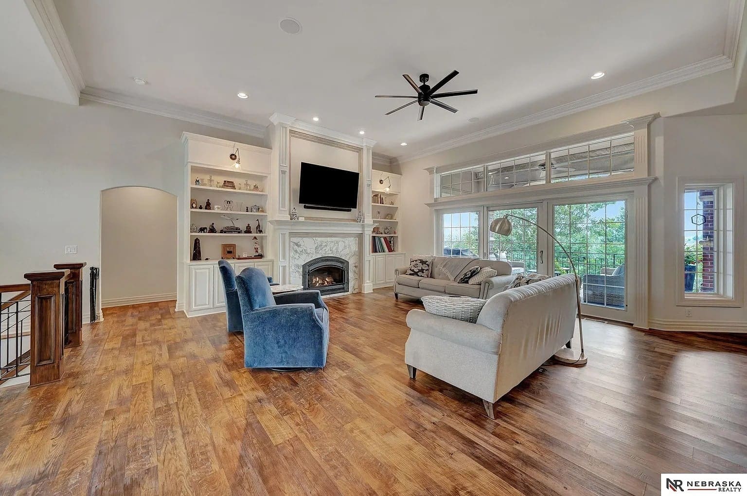 Spacious living room with hardwood floors, large windows, fireplace, and comfortable seating arrangement.