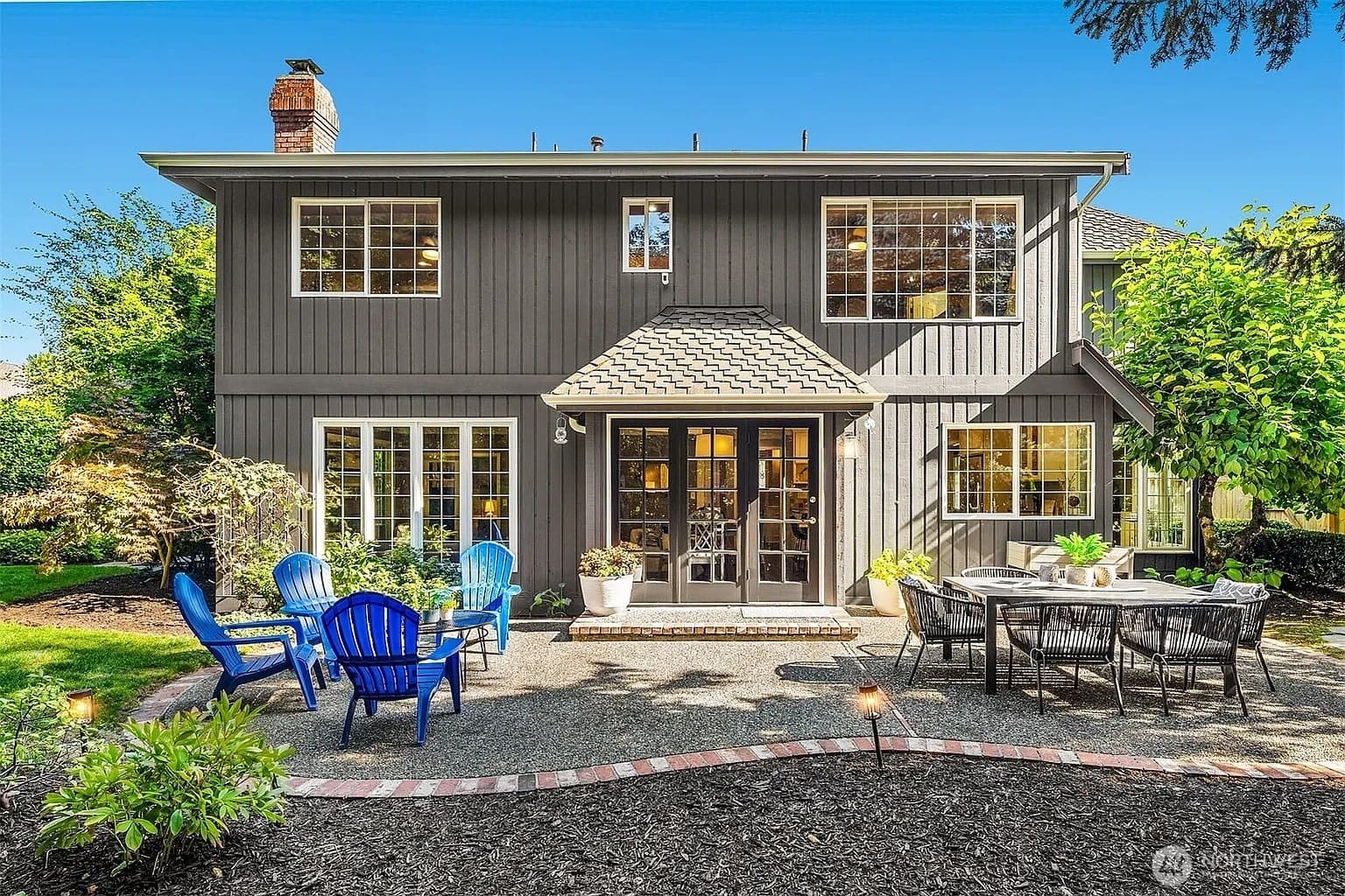 Two-story house with gray siding, patio furniture, and a well-maintained garden in the backyard.