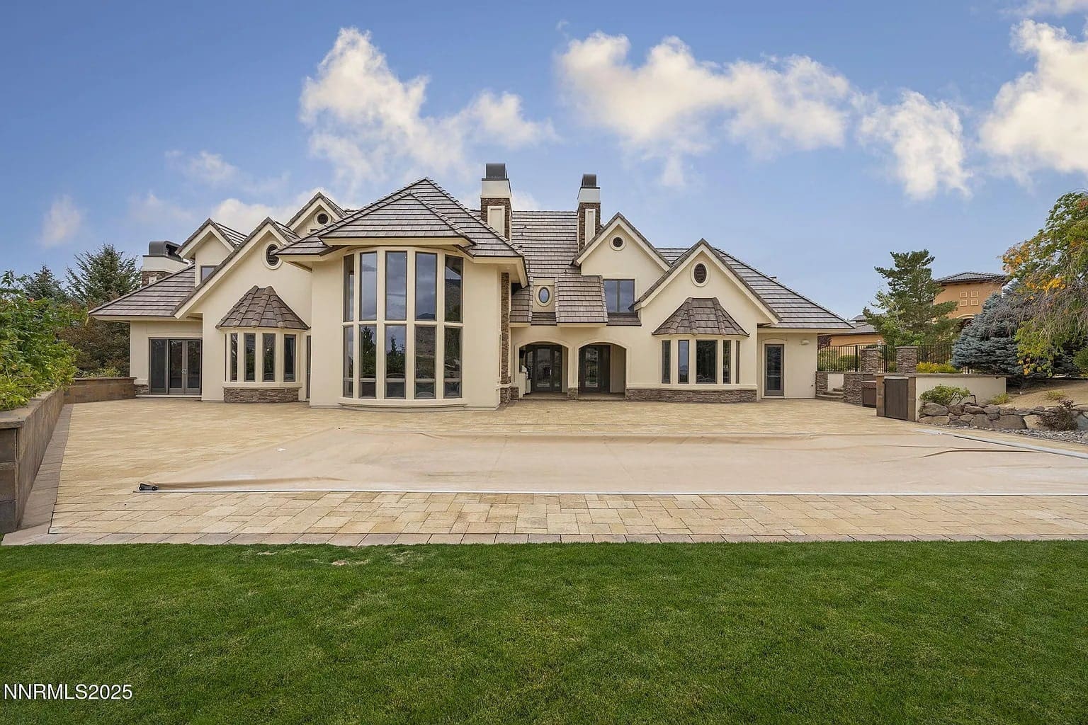 Large modern house with multiple gables, tall windows, and a spacious driveway.