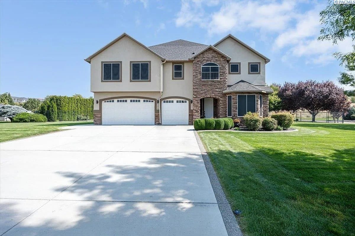 Two-story suburban house with a three-car garage, large driveway, and well-maintained lawn.