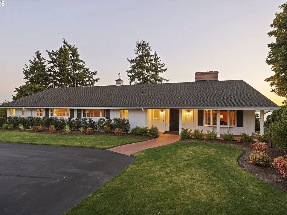 Single-story house with a large front yard, surrounded by trees, at sunset.