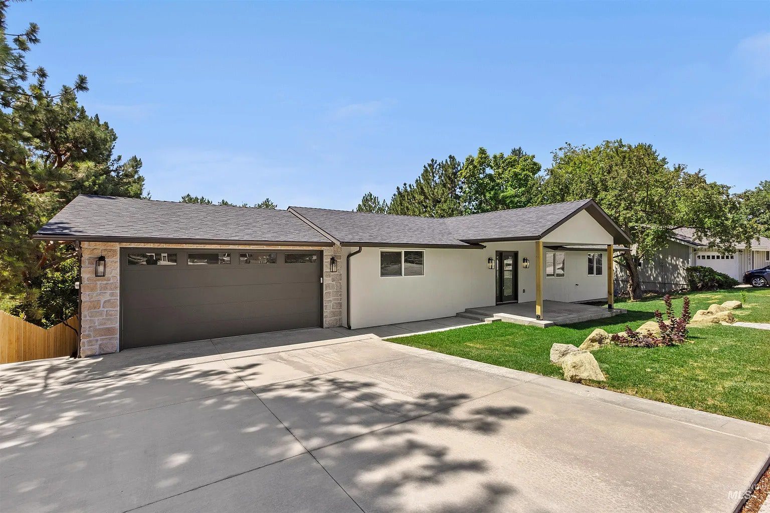 Single-story house with a two-car garage, white exterior, and a well-maintained lawn.