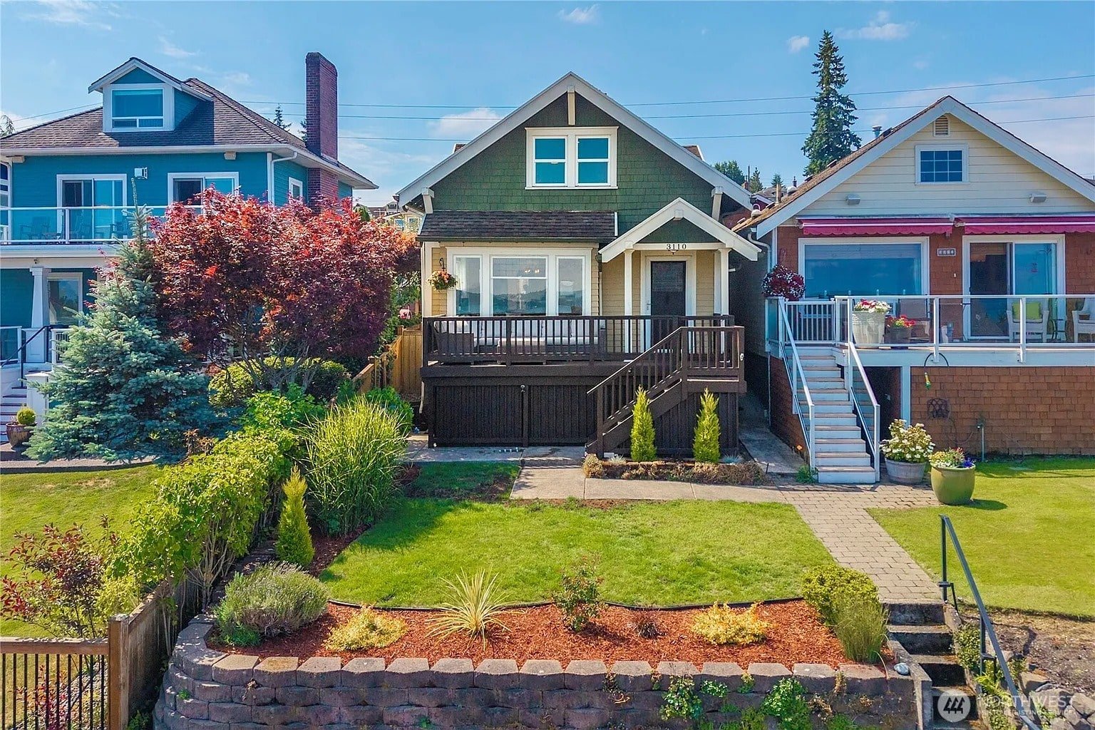 Three colorful houses with small front yards and a clear blue sky in the background.