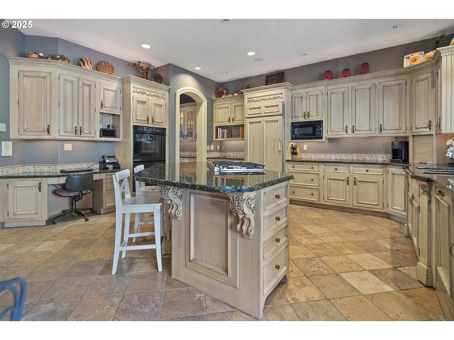 Spacious kitchen with light wood cabinets, central island, granite countertops, and tile flooring.