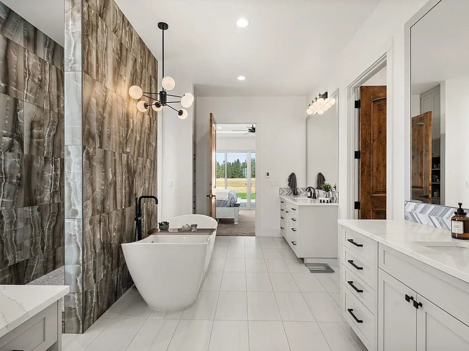 Modern bathroom with freestanding tub, large tiles, double vanity, and contemporary lighting.