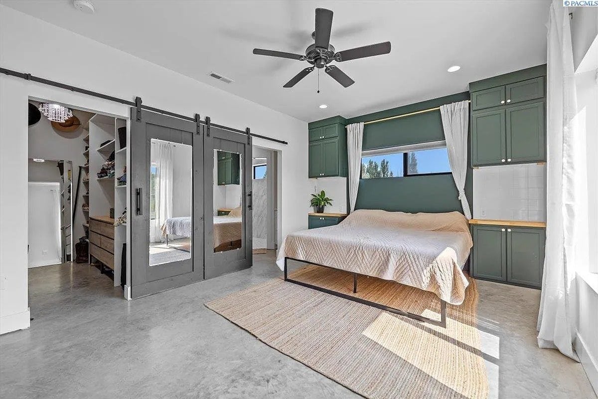 Bedroom with a bed, green cabinets, sliding mirrored doors, and a ceiling fan.