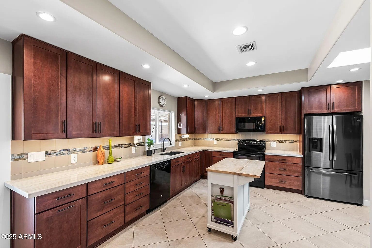 Modern kitchen with dark wood cabinets, stainless steel appliances, and a small island.
