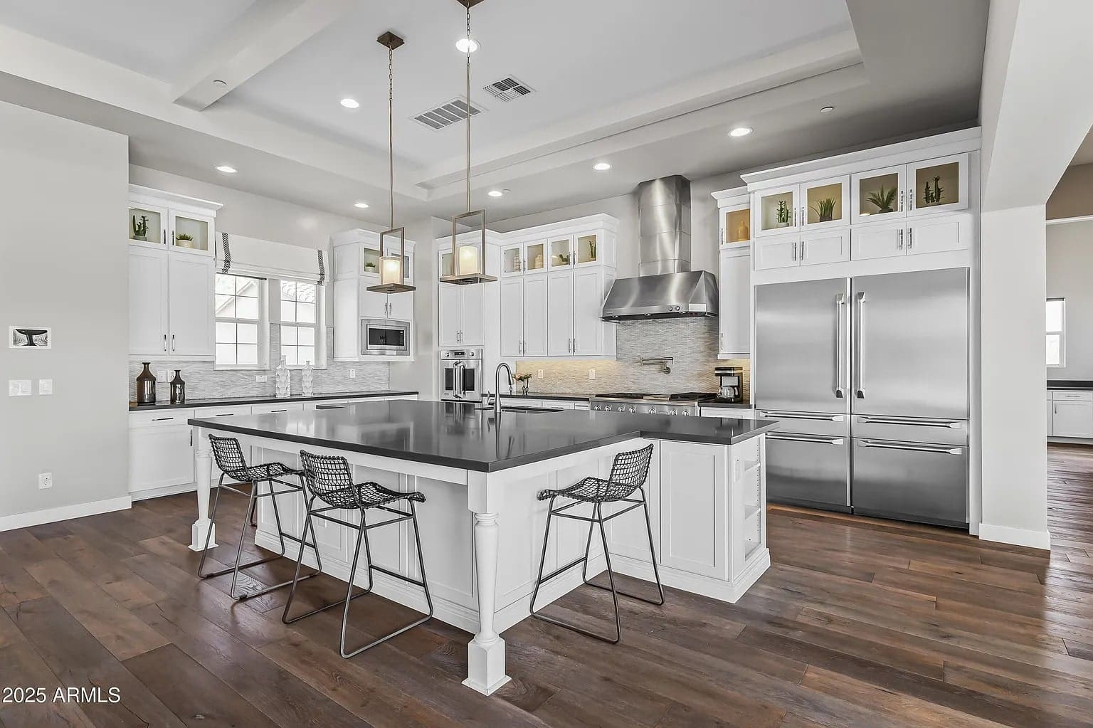 Modern kitchen with white cabinets, large island, stainless steel appliances, and wooden floor.