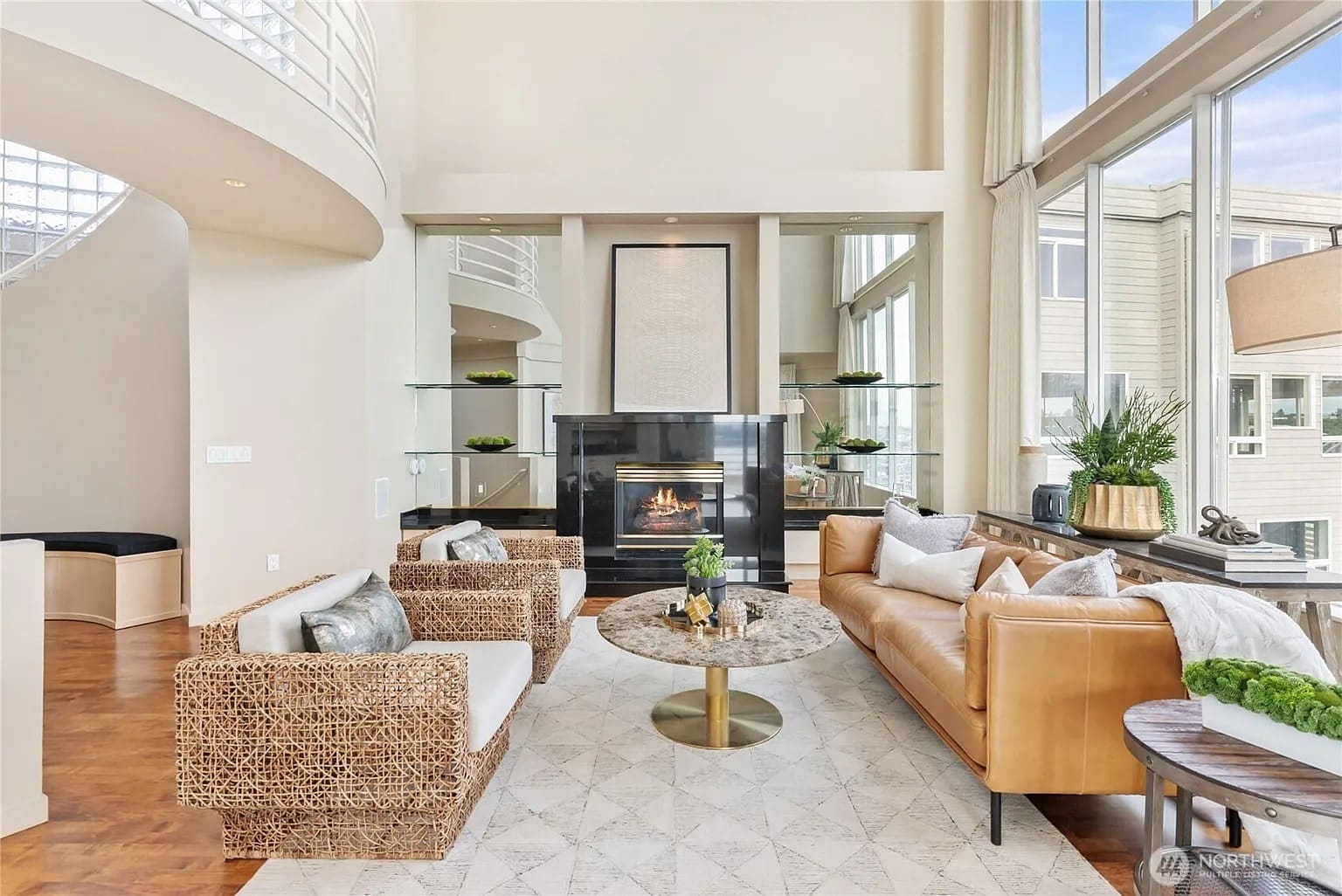 Spacious modern living room with high ceilings, large windows, and a fireplace.