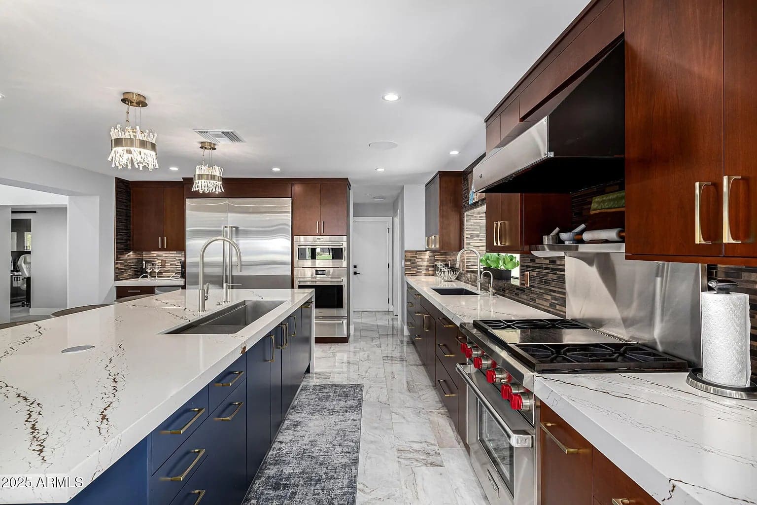 Modern kitchen with dark wood cabinets, marble countertops, stainless steel appliances, and a large island.
