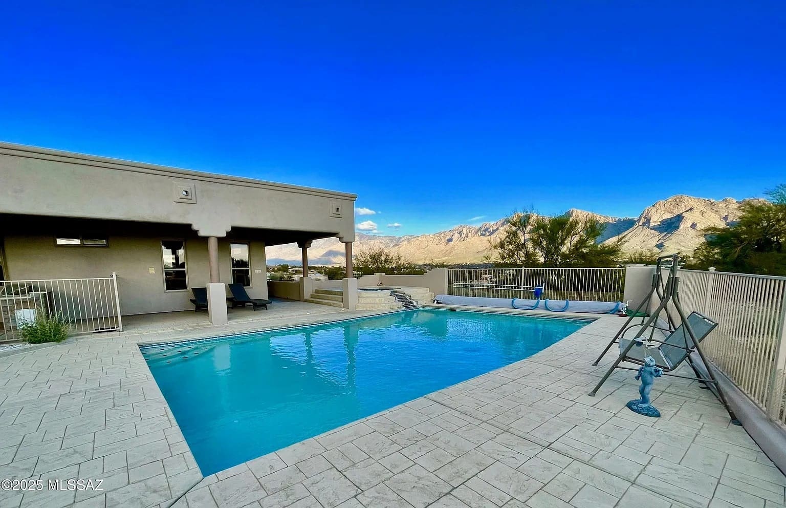 Outdoor pool with mountain views, surrounded by a patio and a covered seating area.