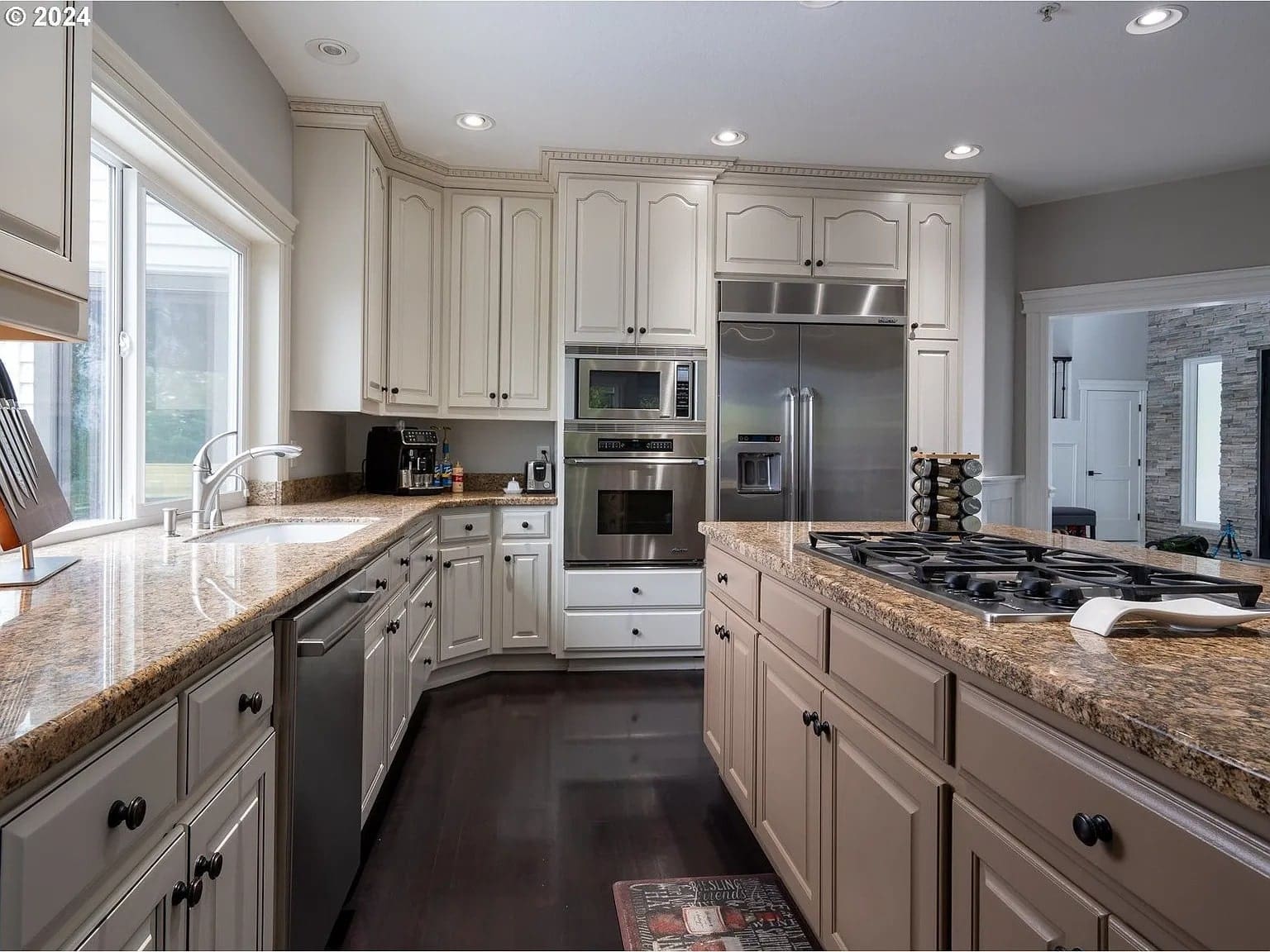 Modern kitchen with granite countertops, stainless steel appliances, and dark wood flooring.