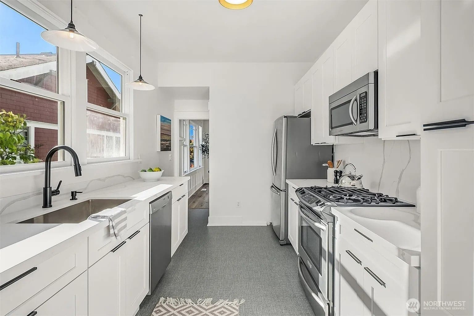 Modern kitchen with white cabinets, stainless steel appliances, and a farmhouse sink. Bright natural light.