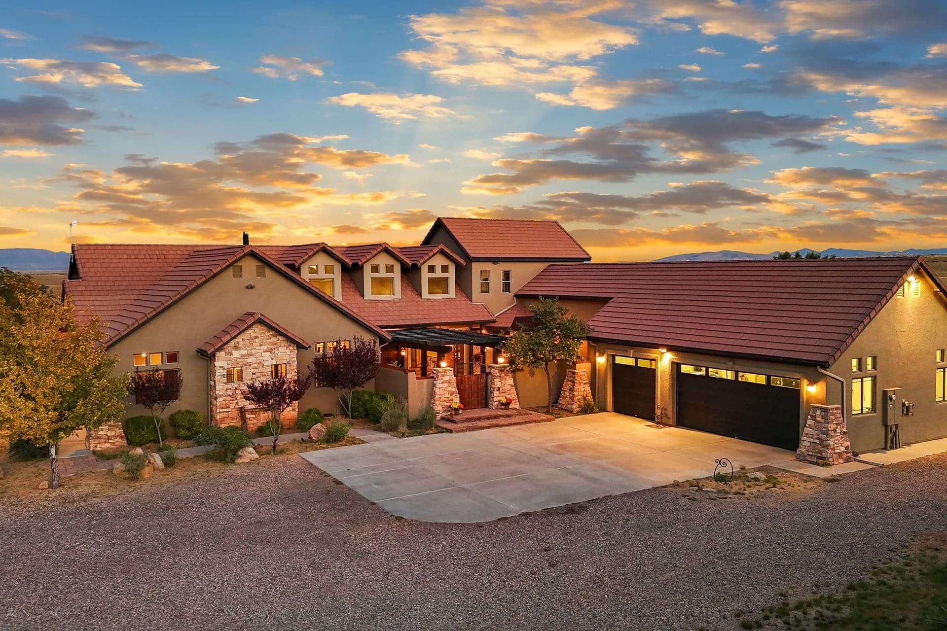 Large house with stone accents and a three-car garage at sunset.