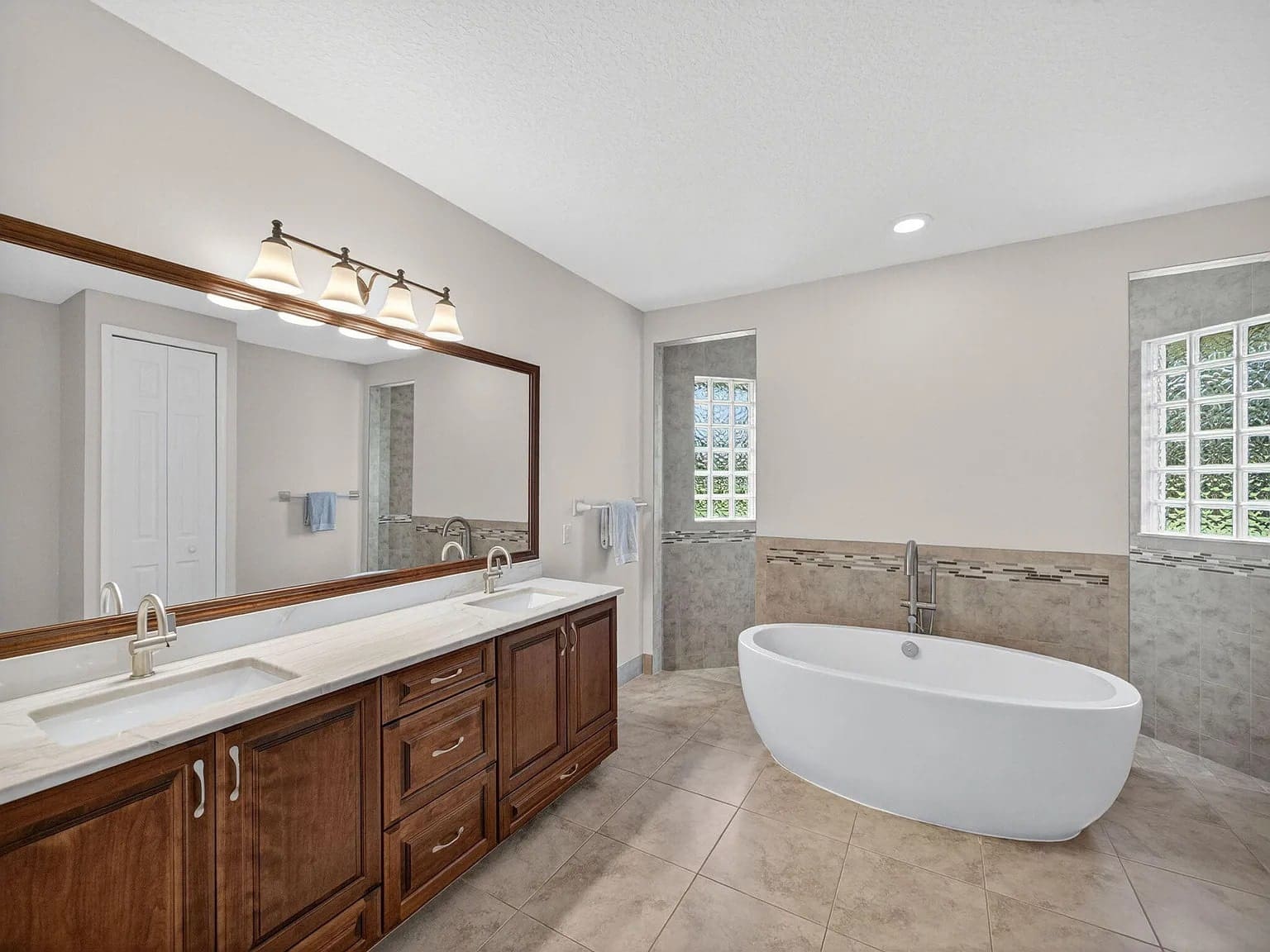 Spacious bathroom with a double sink vanity, large mirror, and a freestanding bathtub.
