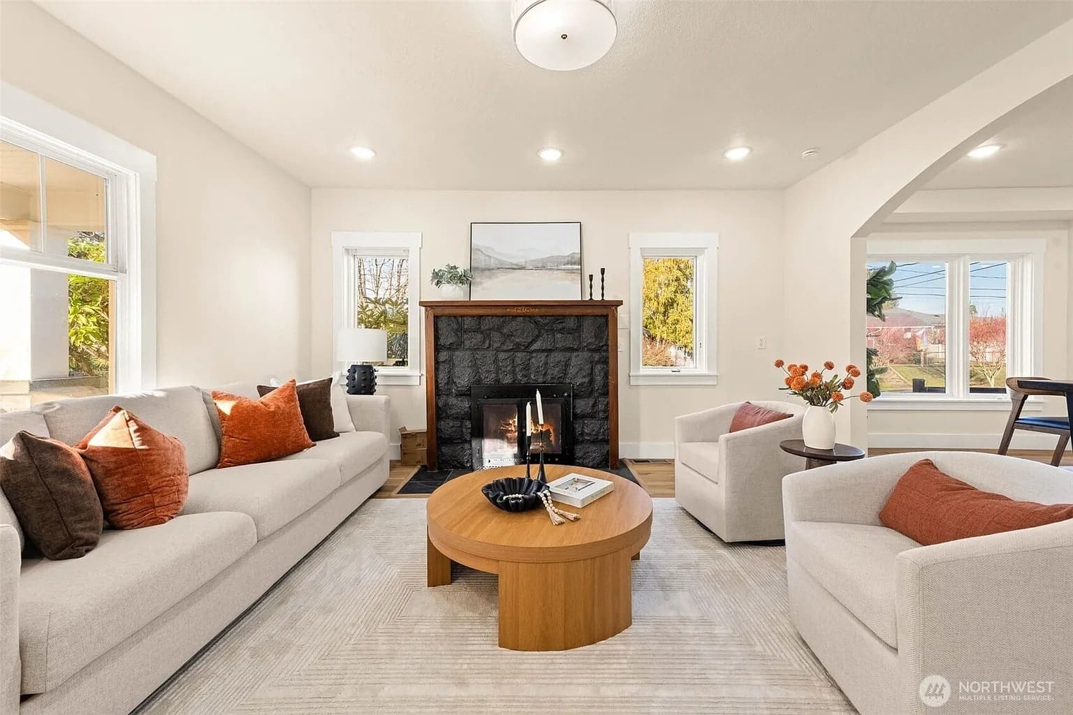 Living room with beige sofas, a round wooden table, and a fireplace with a black surround.