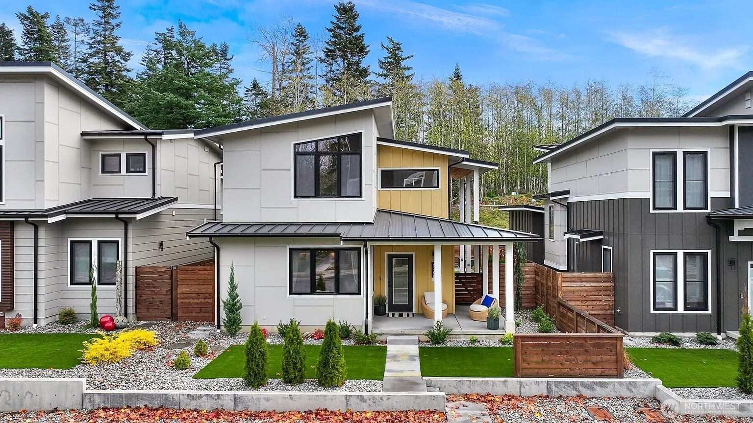 Modern two-story house with a landscaped front yard and surrounding trees.