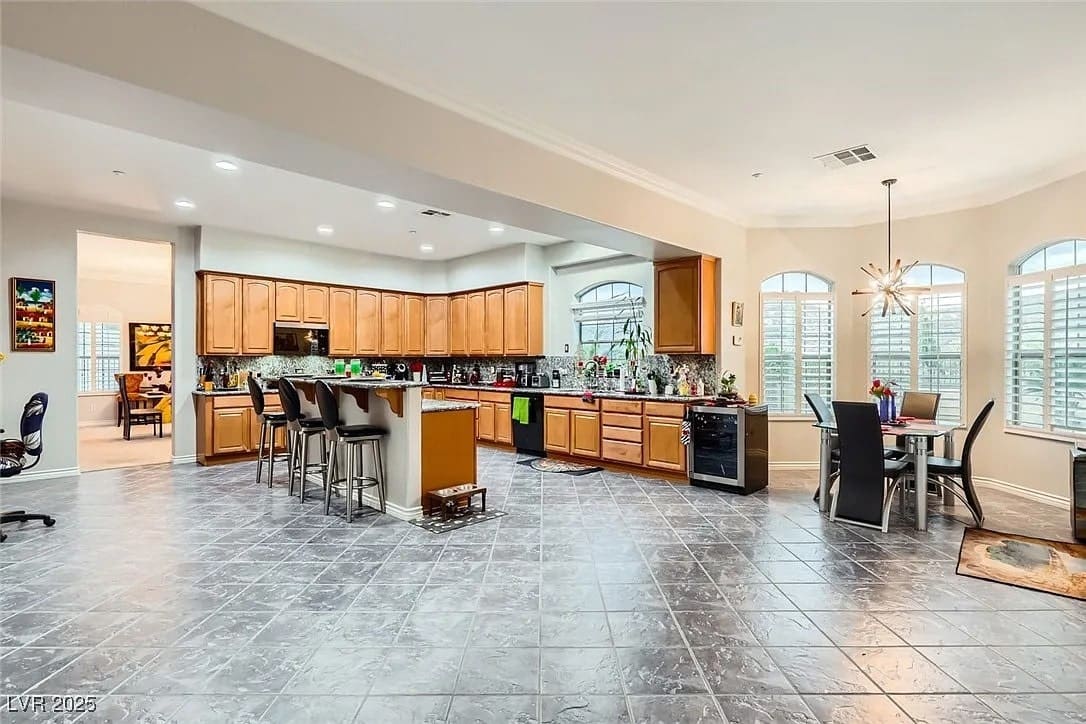 Spacious kitchen with wooden cabinets, large island, dining area, and tiled flooring.