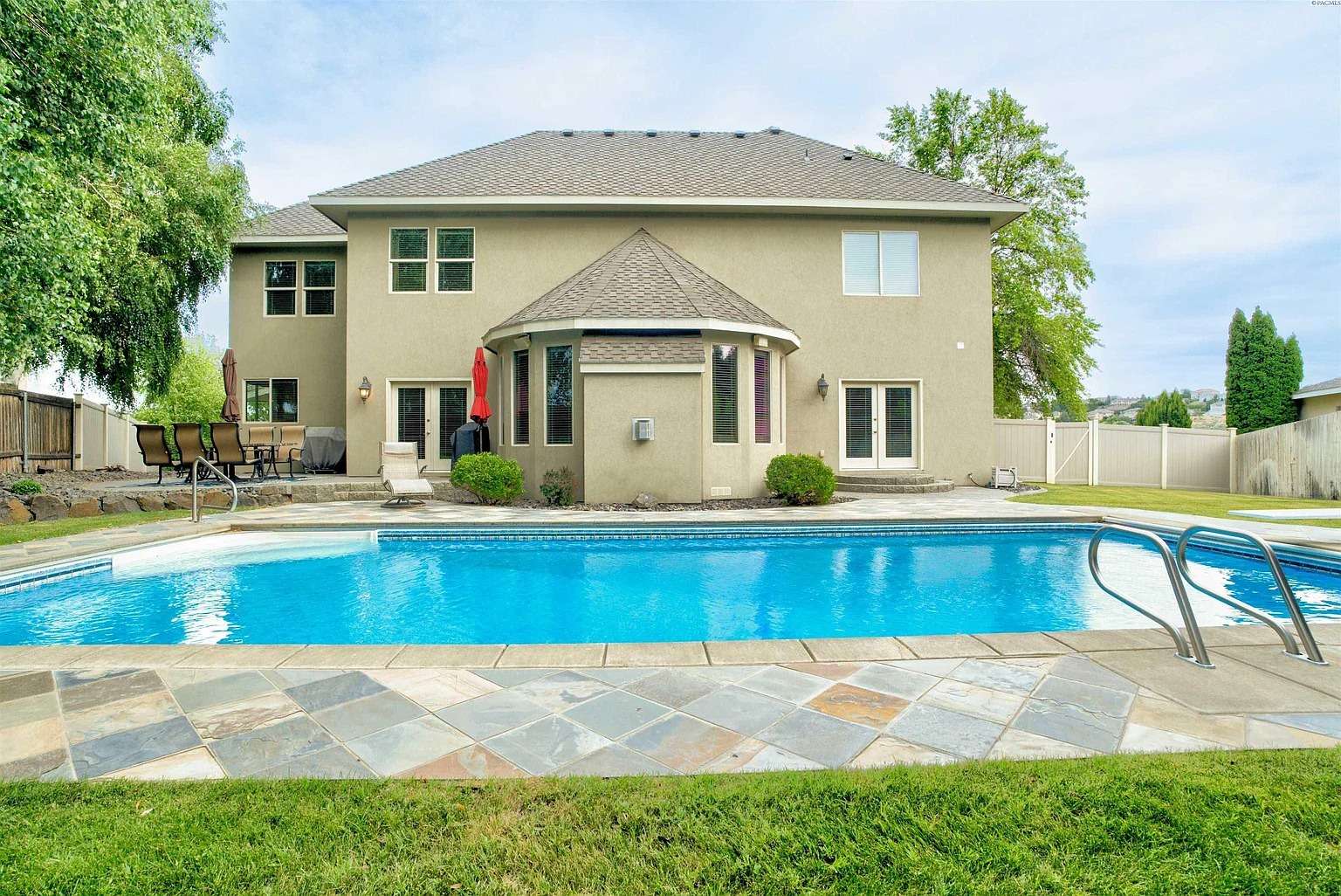 Backyard view of a two-story house with a swimming pool and patio furniture.