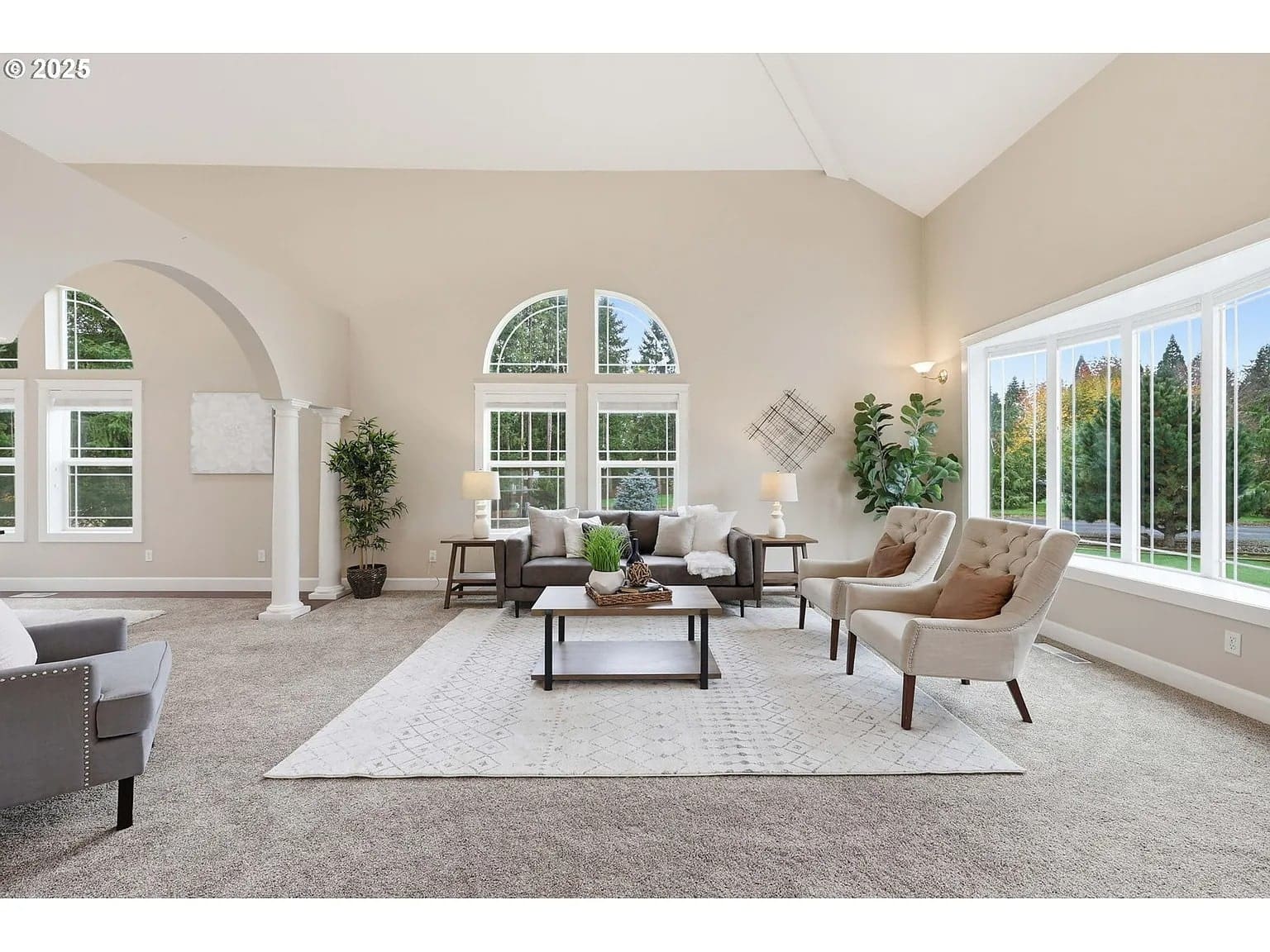 Spacious living room with large windows, neutral decor, and modern furniture.