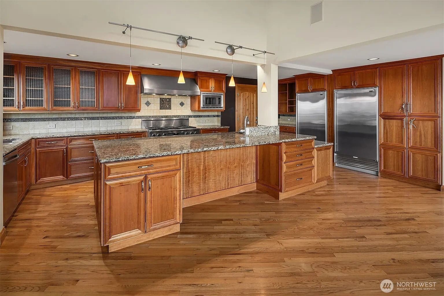 Spacious kitchen with wooden cabinets, granite countertops, stainless steel appliances, and hardwood flooring.