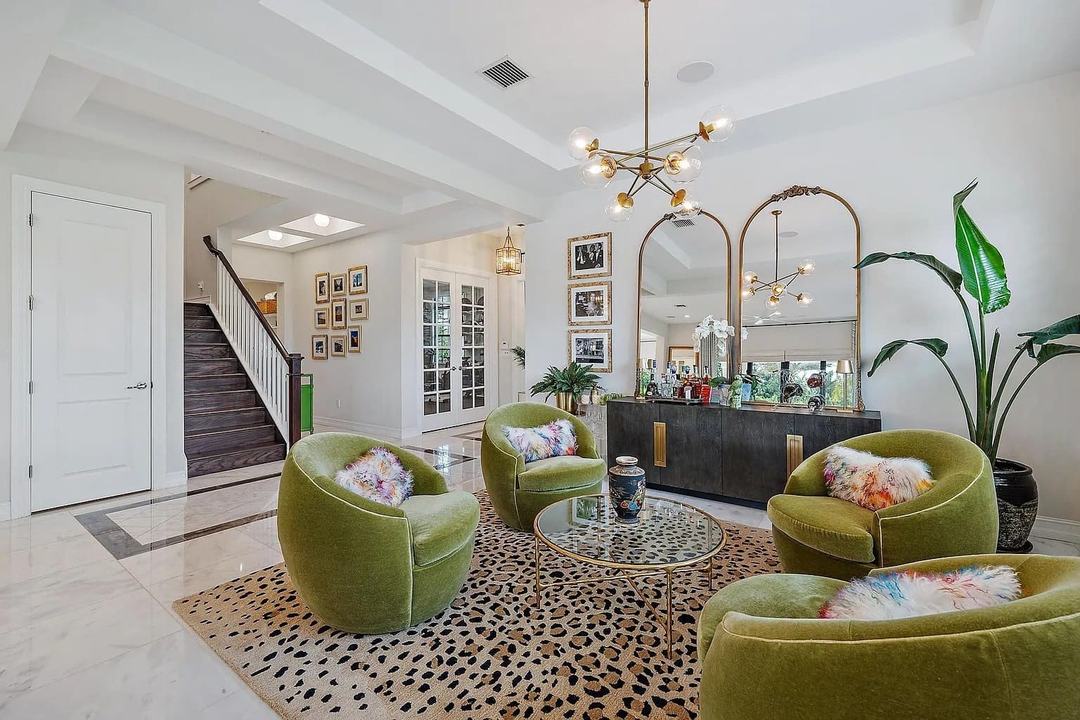 Modern living room with green chairs, leopard print rug, large mirrors, and decorative plants.
