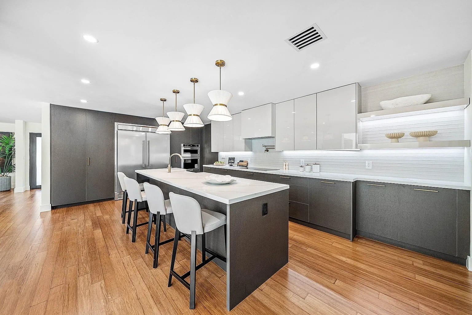 Modern kitchen with a large island, bar stools, pendant lights, and sleek cabinetry.