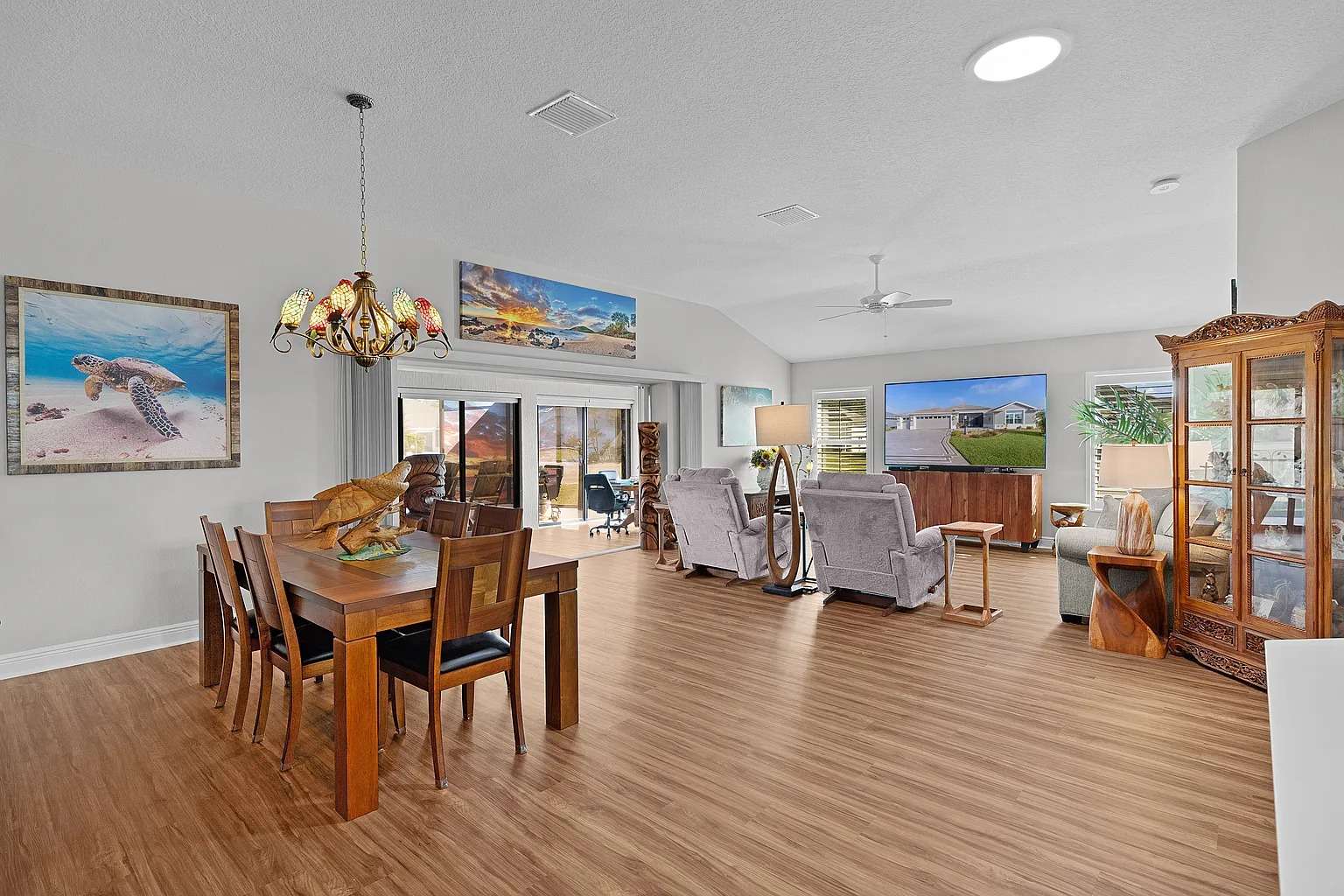 Open-concept living and dining area with wooden floors, modern furniture, and large windows.